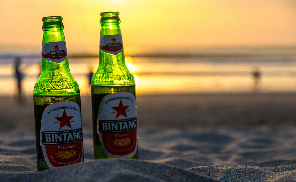 Two Bintang beers on resting on the sand at sunset.